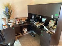 Desk with attached storage hutch, five drawers, and under-mounted light in laminate finish with various office items placed on it.