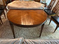 Top view of wood dining table fully extended with two leaves in place, surface with visible wood grain and some nicks and scratches.