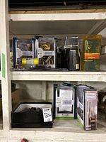 Two shelves with various door lock products. Top shelf includes boxed Schlage and Weiser locks. Bottom shelf has loose used door hardware in a box and other boxed items.