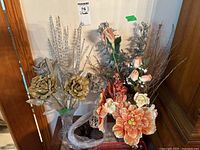 Front view of two glass vases containing faux floral arrangements with decorative balls on the side.