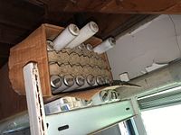 Fluorescent light tubes stored in a cardboard box on a shelf with protective fiber dividers.
