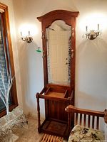 Front view of the wooden hall tree showing mirror with etched border, brass hooks, and upper crown molding.