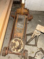 Top view of the orange 2 1/2 ton hydraulic floor jack showing rust on the lifting pad and wear on the frame.