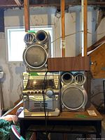 JVC MX-KB2 stereo system with two speakers on a table in garage setting.