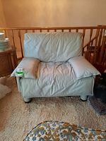 Front view of light-colored leather armchair with creasing and wear on cushions and seat.