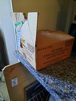 Cardboard box labeled 'Chocolate Pudding and Pie Filling' repurposed for storage of pasta and kitchen items.