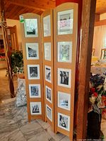 Full view of the wooden folding screen with three panels, each panel holding five framed black-and-white photographs.