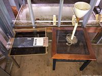 Two side tables with a table lamp placed on one, and a glass shelf behind, showing overall lot contents.