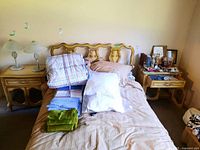 Two wood vintage style side tables next to a bed, showing overall size and shape with carved details and curved legs.