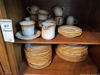 Front view of all stoneware items arranged on wooden shelves