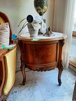 Full view of wood side table with stone top holding decorative lamp and other items