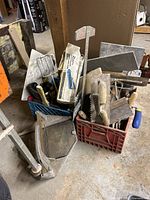 Mix of tiling tools including trowels, mortar mixer attachment, and floats in two crates on workshop floor.