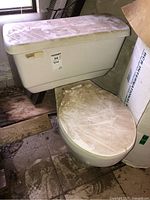 Full view of the American Standard two-piece toilet showing tank and toilet seat covered in dust and dirt.