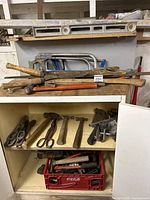 Shelving with multiple hammers, scissors, pliers, nails, and other hand tools.
