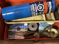 Photo of blue Mastercraft propane tank, steel strapping, and other small hand tools inside red tool box.