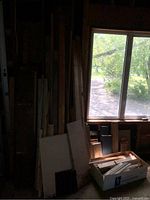 Wood scraps leaning against wall near window with natural light showing variety of sizes and types