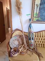 Overall lot showing mask leaning on couch, round woven wall decor, and duck-shaped baskets arranged on couch seat.