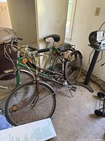 Two vintage Sears bicycles leaning against a wall indoors showing frame, tires, and saddle seats.