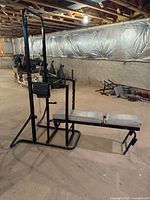 Front and side views of black metal frame workout bench with gray padded seat and backrest, configured for dips and pull-ups.
