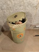 Closed decorative metal trash can with sunflower decoration, showing overall condition and design