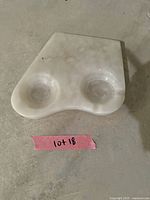 Double ashtray carved from white onyx stone, showing two round bowl-shaped indentations for ash or cigarette rests. Smooth polished natural stone surface with markings.