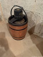 Front-side view of the electric barrel form ice cream maker showing wooden barrel exterior and black motorized top with handle.