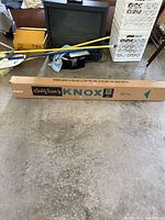 Knox projector screen packaging box on floor with some surrounding household items