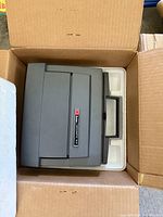 Kodak Instamatic M80 projector in original packaging inside a cardboard box with foam insert.