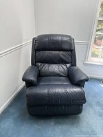 Front view of dark slate blue leather recliner chair showing overall worn condition and intact mechanical reclining.