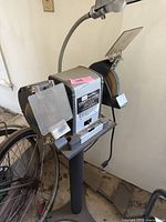 Front and side view of the Sears Craftsman bench grinder showing overall structure, grinding wheels, and attached lamp.