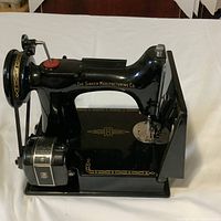 Left-side view of the machine showing Singer Manufacturing Co logo, gold decals, belt and motor assembly