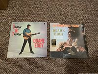 Front covers of two sealed Duane Eddy vinyl LP records 'Twistin' N Twangin'' and 'The Twangs The Thang'. Both albums show the artist holding guitars.