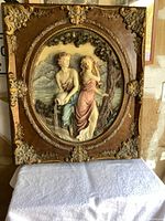 Full view of the large framed porcelain plaque showing the man and woman in classical attire in a scenic outdoor setting with a decorative, textured frame.