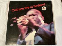 Front cover of the Coltrane Live At Birdland LP record, showing the blurred image of Coltrane playing saxophone and red title text