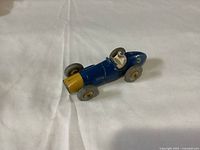 Top-down view of the vintage blue and yellow Dinky Ferrari model car featuring the driver and tire details.