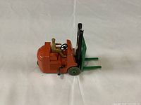 Side view of the orange and green lift truck with driver seated, showing overall condition and details.