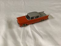 Front side view of the Dinky Toys Packard Clipper model car showing orange and grey two-tone paint and detailed chrome accents.