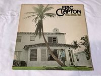 Front cover of Eric Clapton's 461 Ocean Boulevard vinyl LP showing a white house with palm tree and Eric Clapton standing on porch.