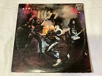 Front cover of the Kiss Alive! vinyl gatefold album showing the band in stage costumes with smoke effects