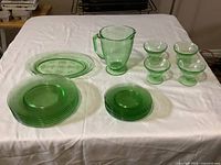 Full view of the entire glassware set on white tablecloth, showing all plates, pitcher, and fruit nappies.