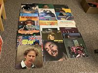 Overview of 22 vinyl LP records laid out on floor showing various artist album covers including The Bachelors, Steve Winwood, and Henry Gross.