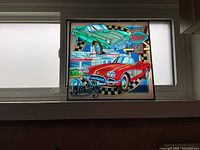Full view of vintage stained glass panel hung in window showing colorful classic cars and diner motif.