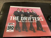 Front cover of the sealed vinyl record by The Drifters titled 'Save the Last Dance for Me' showing the four band members against a red background with 180 gram limited edition label.