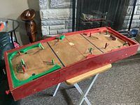 Full view of the vintage wooden framed table top hockey game showing red and green goals, playing surface, and player control rods.