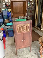 Full view of the Premier Victrola in an oak cabinet, showing decorative front panel and cabinet doors closed.