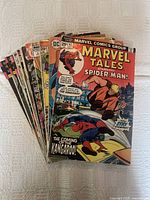 Stack of 16 assorted Marvel and DC comic books from 1970s and 1980s, showing front covers with Spider-Man prominently featured on top.