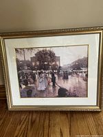 Framed print showing a wedding party scene outside Notre Dame, Paris, with people in period dress walking near outdoor lamps and buildings.