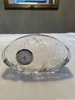 Front view of the crystal decorative clock showing clear crystal body with floral etching design and inset analog clock.