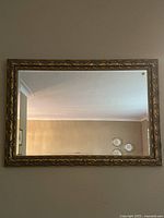 Front view of large rectangular wall mirror showing ornate gold wood frame with carved decorative details.