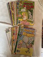 Bundle of Richie Rich comic books stacked and fanned out on white fabric.